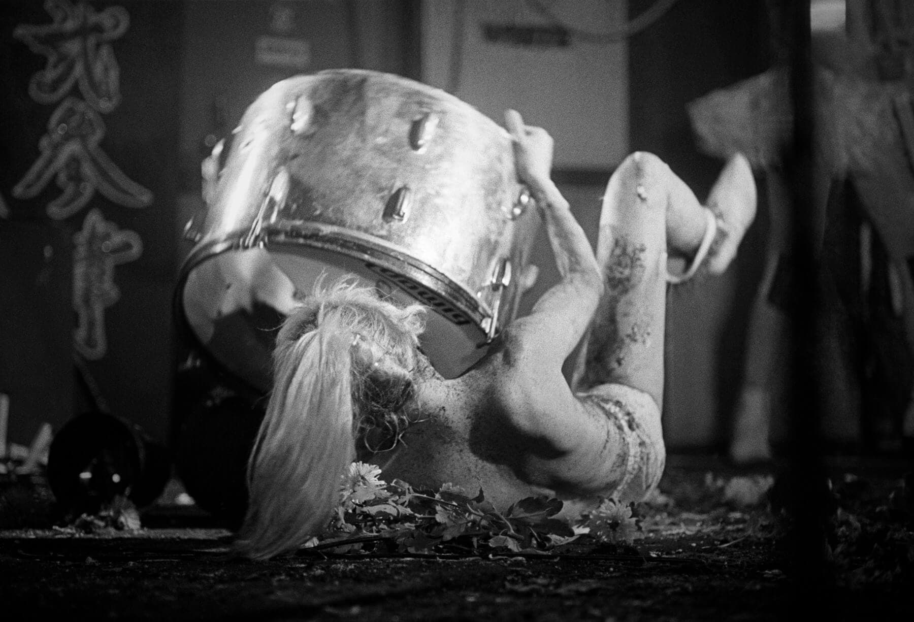 Punk rock band lead singer Wendy O Williams and the Plasmatics lies down on stage during a performance in a black and white image.