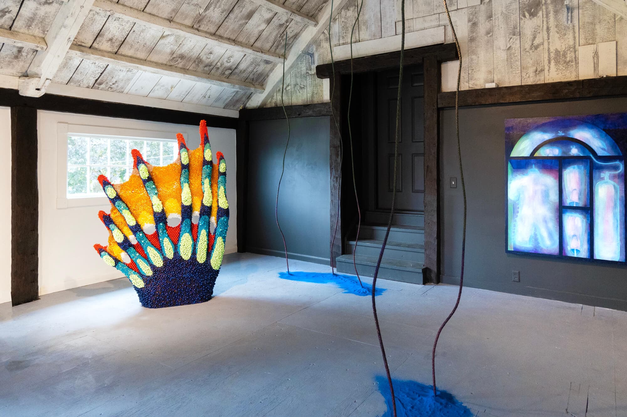 An aquatic installation on display rising beneath a gallery's A-frame ceiling.